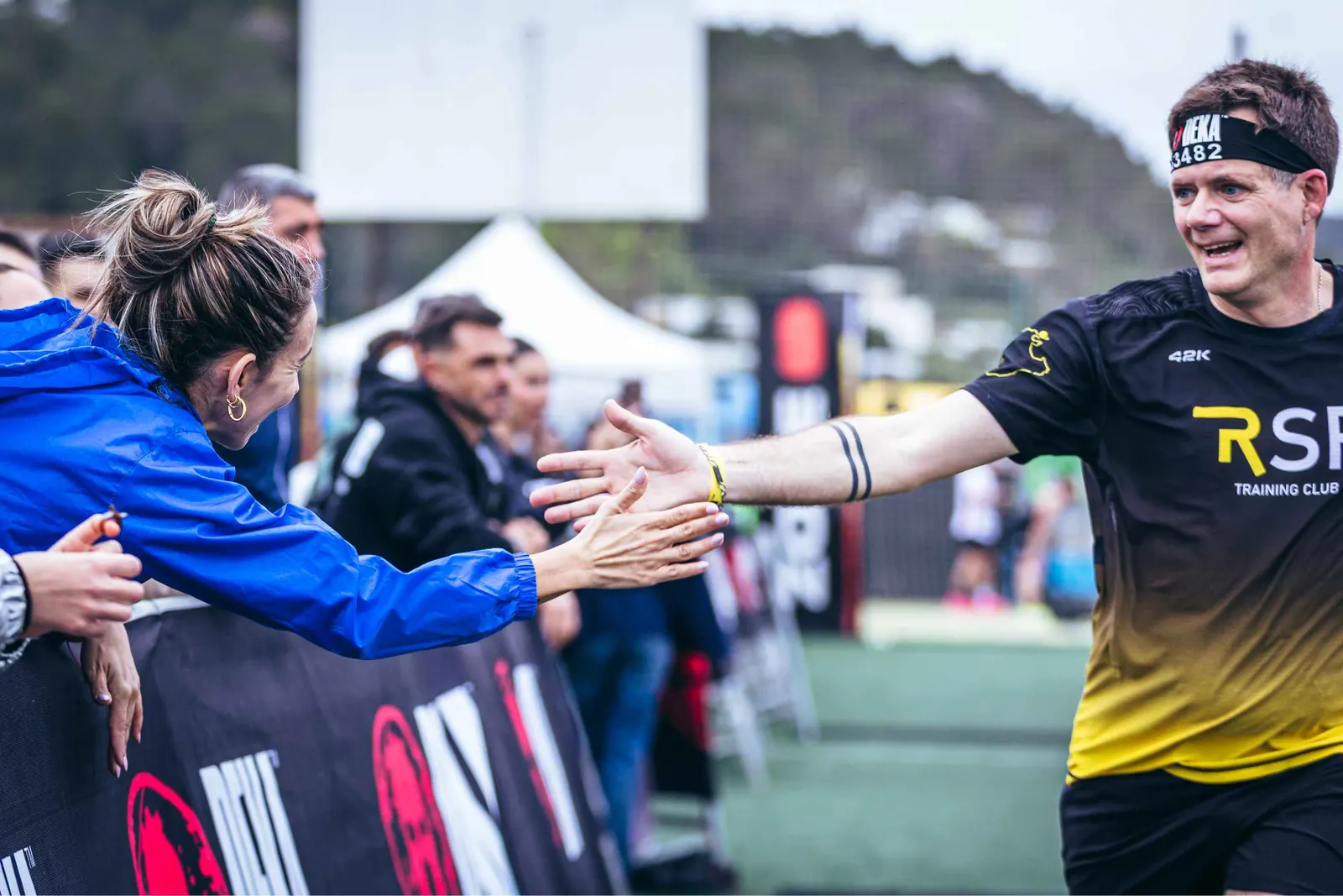 Atleta chocando la mano con una persona que le anima tras la valla en DEKA Ibiza
