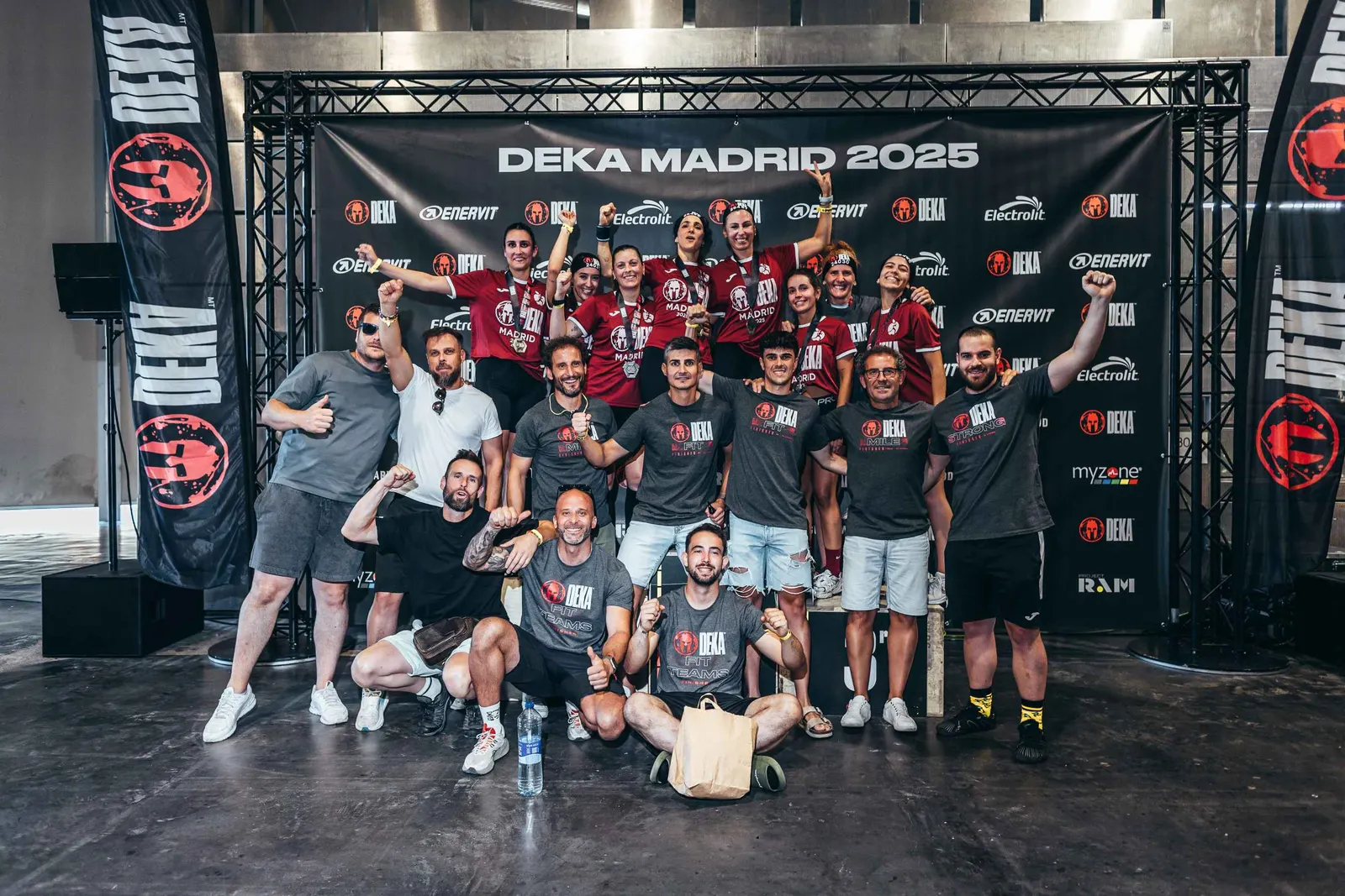 Grupo de atletas con sus medallas celebrando frente al photocall de DEKA Madrid 2025