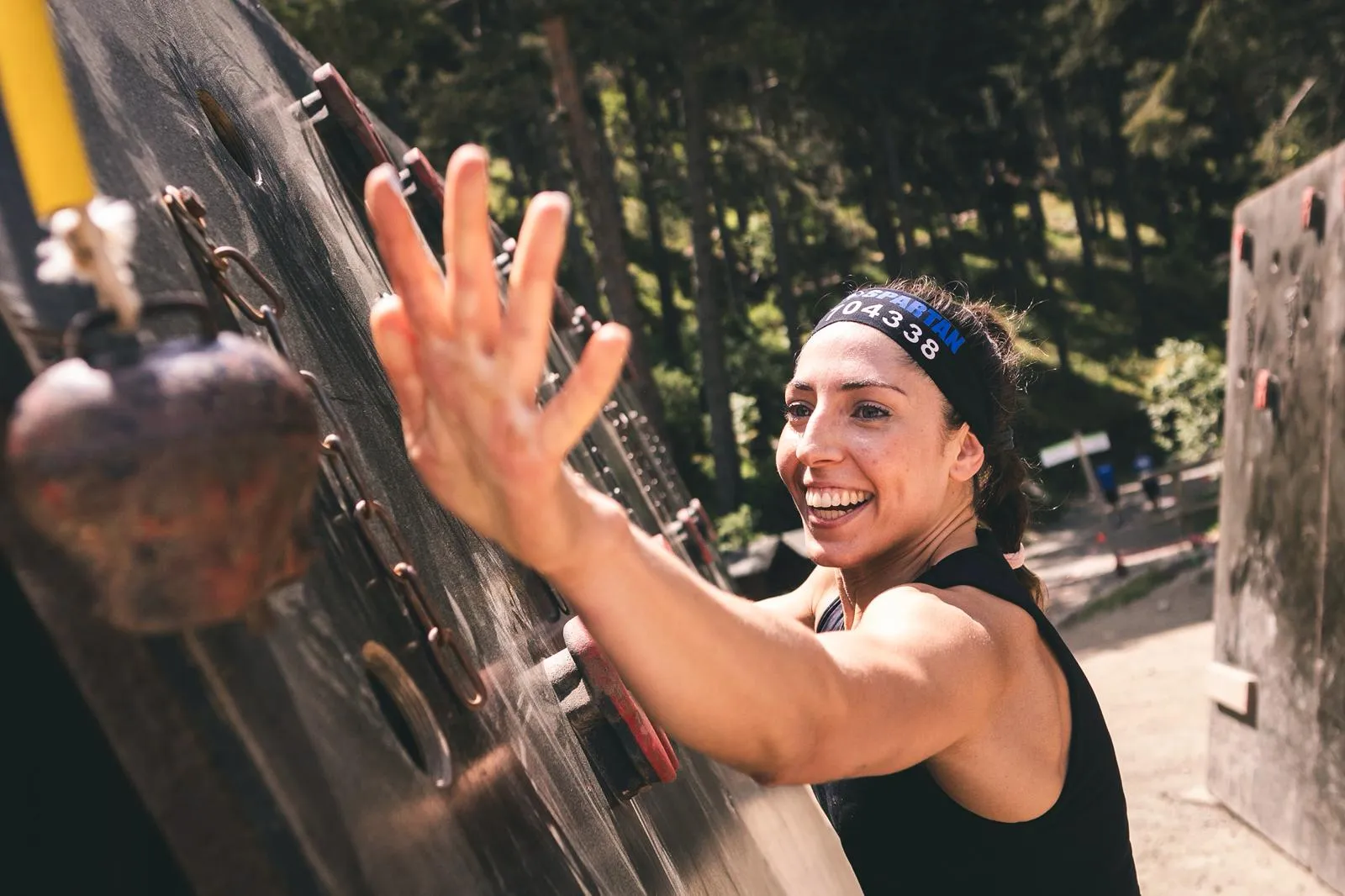 Corredora con su dorsal en la cinta sonriendo en un muro de la Spartan de Encamp